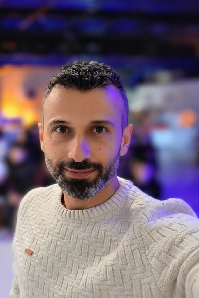 Sinan Köse salonda, gerisindeki insanlar bulanık halde.